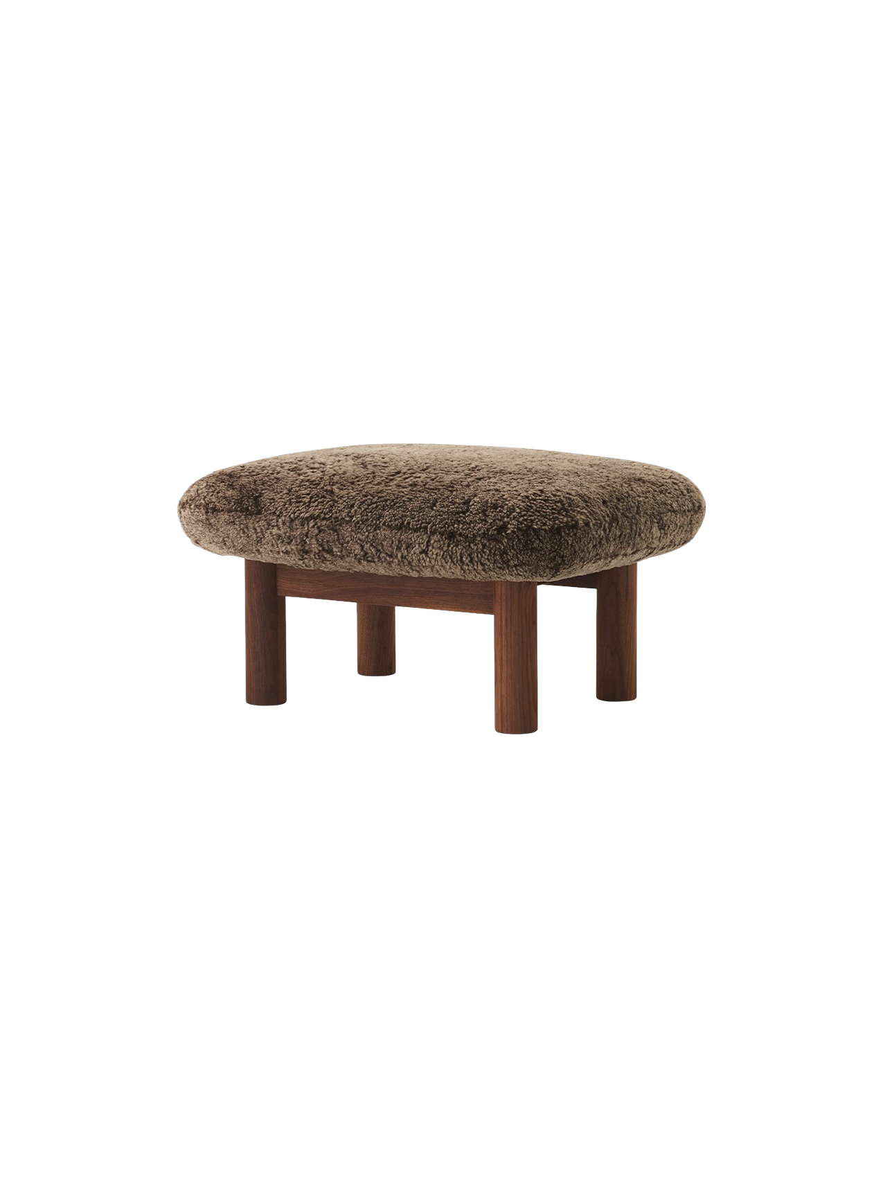 The Brasilia Ottoman in walnut wood with a brown sheepskin upholstery, seen from an angle against a black background.