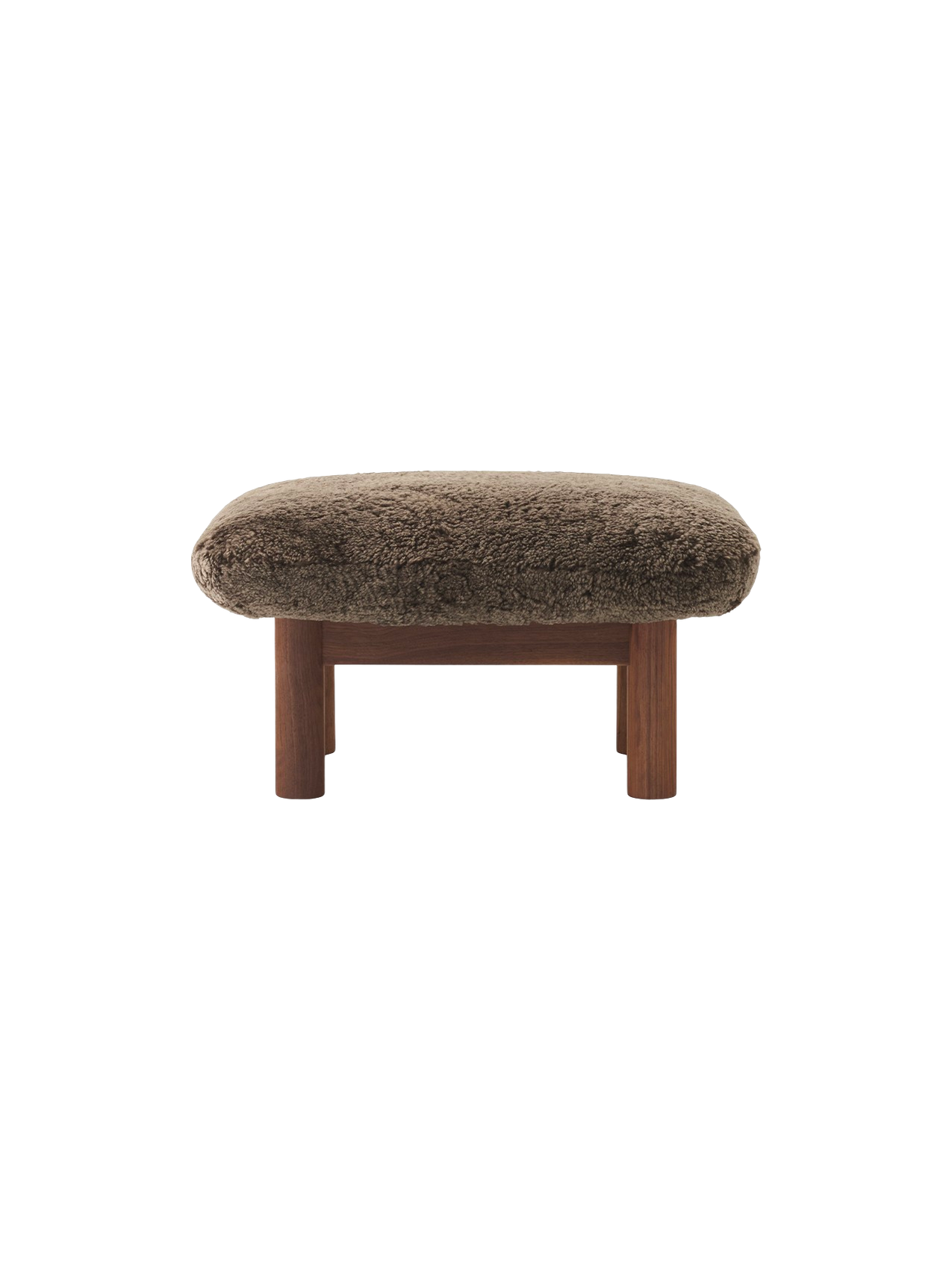 A front-on view of the Brasilia Ottoman, upholstered in brown sheepskin, with a dark walnut frame and four thick legs.