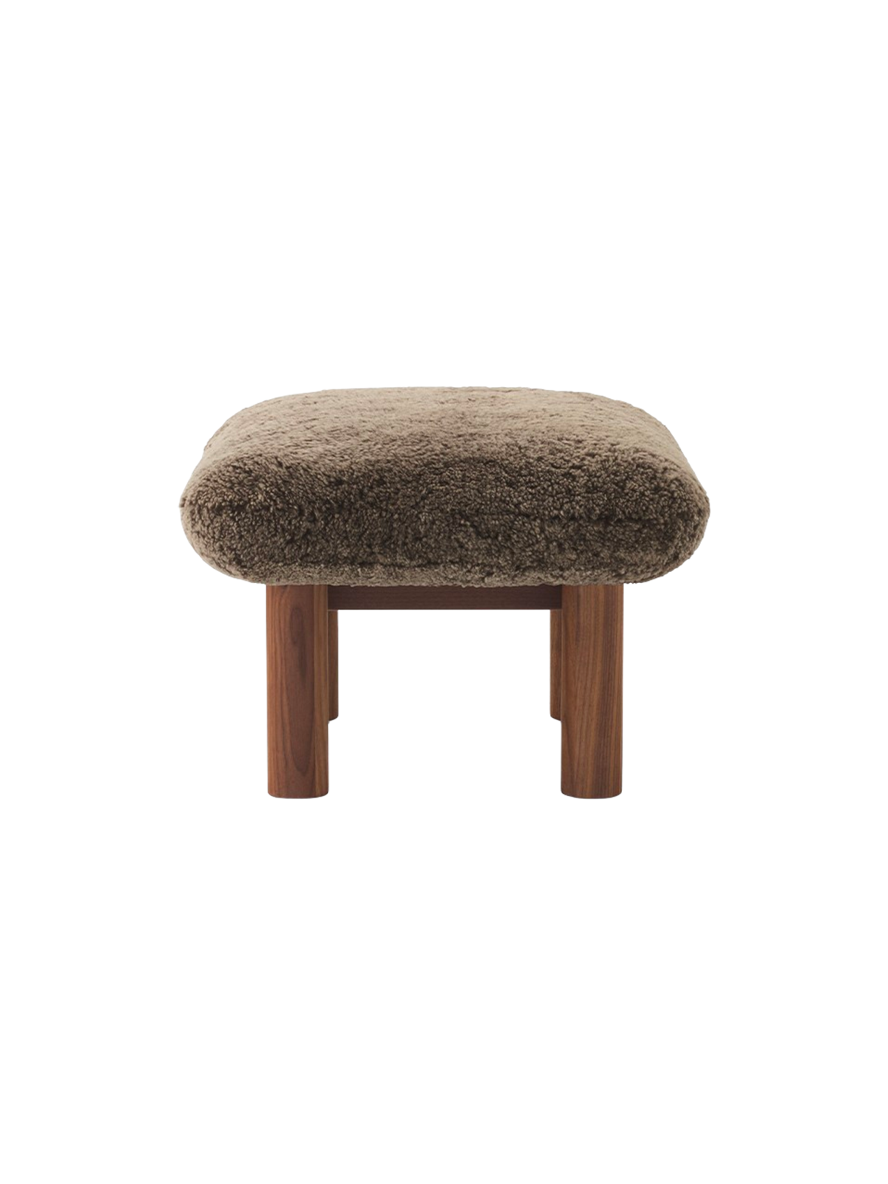 Side view of the Brasilia Ottoman, featuring a plush brown sheepskin cushion and robust, cylindrical legs in walnut wood.