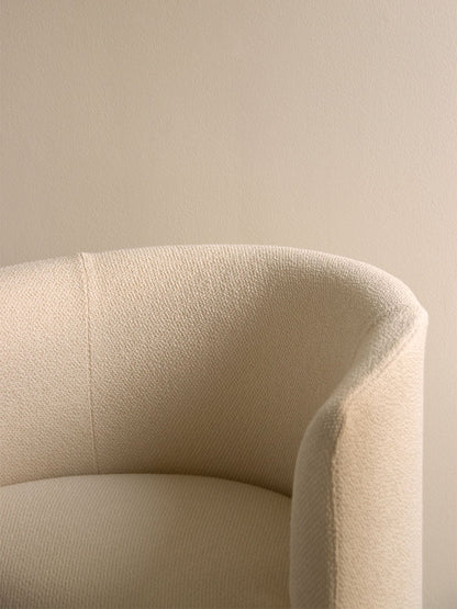 A close-up of the Tearoom Club Chair, showing the texture and curve of its off-white loose cover against a beige wall.