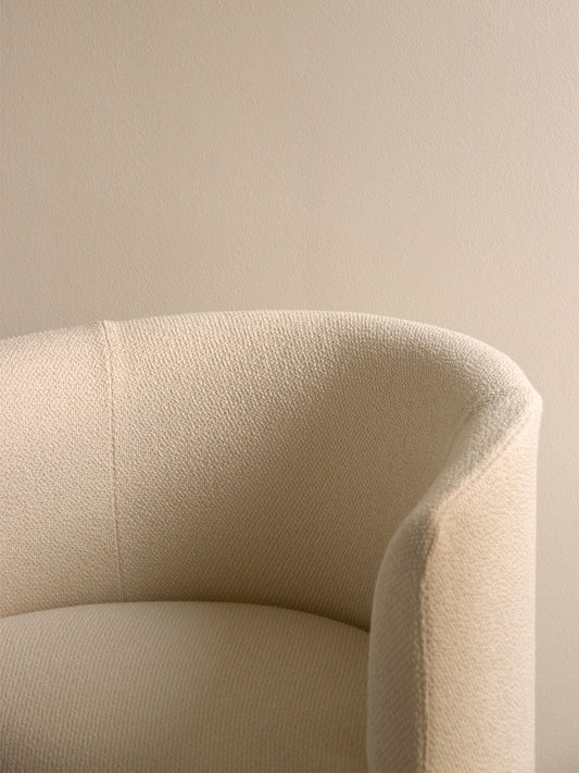 A close-up of the Tearoom Club Chair, showing the texture of its light-coloured woven upholstery and its gently curved form.
