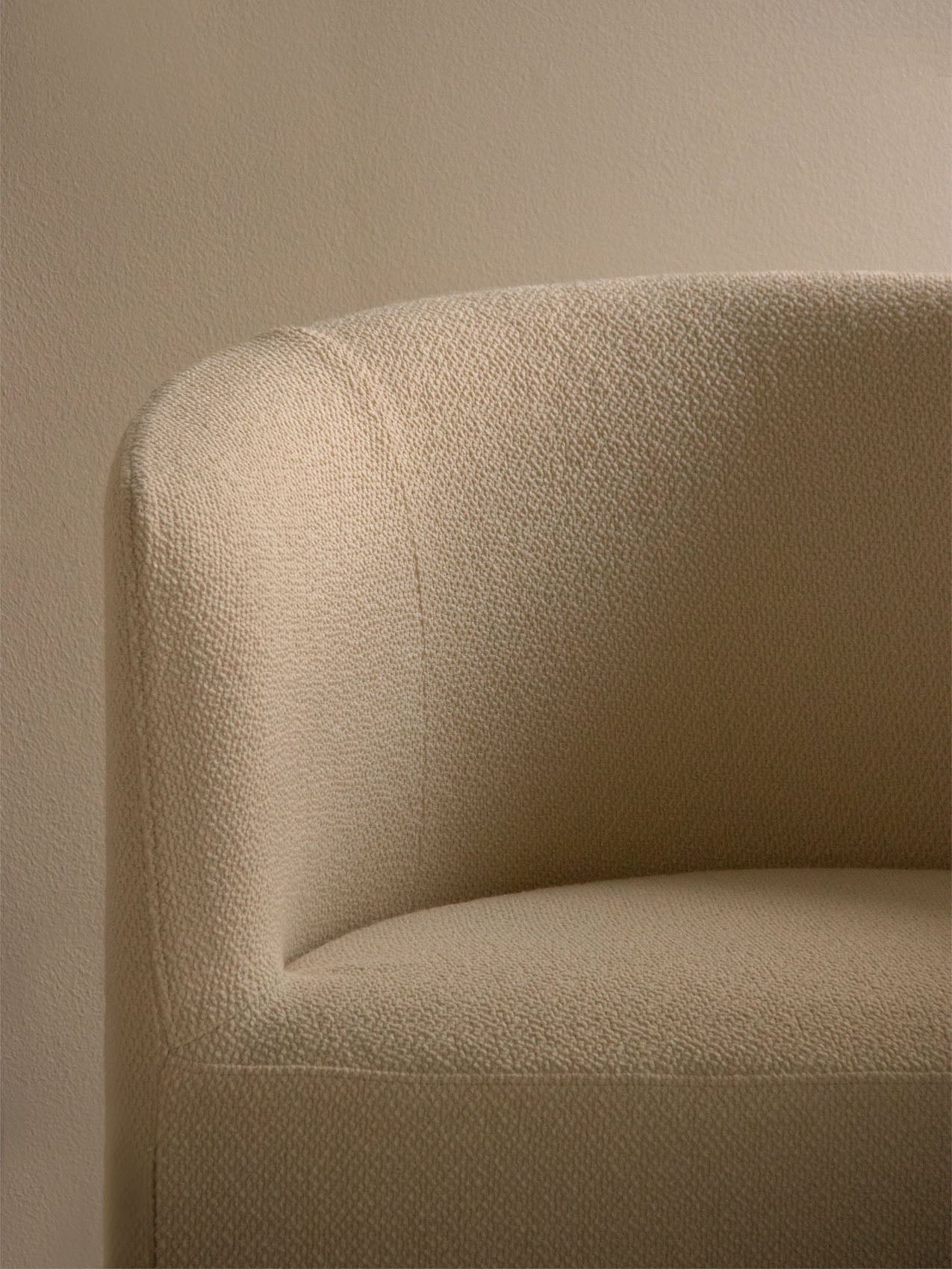A close-up of the Tearoom Lounge Chair's loose cover, showing the textured beige bouclé fabric on its curved back.