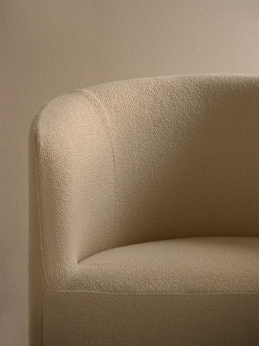 A close-up of the Tearoom Lounge Chair's curved arm, highlighting the detailed, nubby texture of its light beige loose cover.